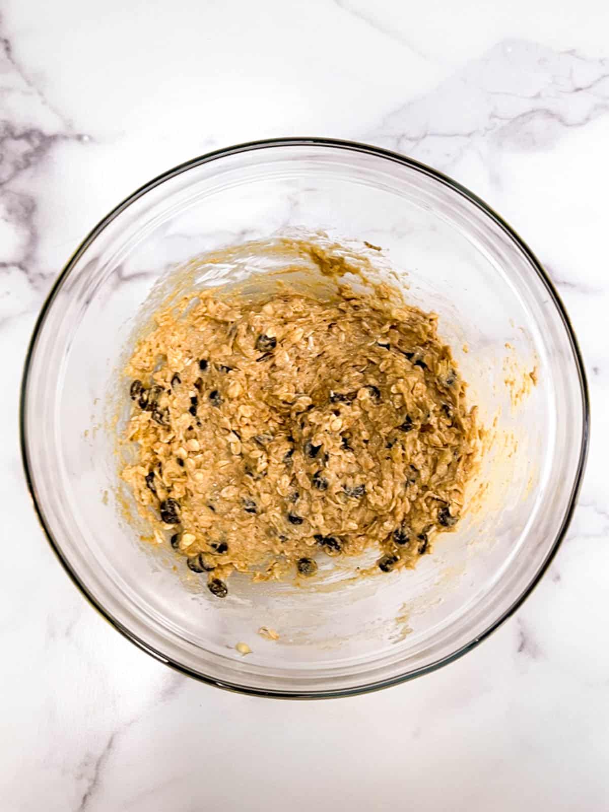 A bowl of oatmeal cookie dough with chocolate chips.